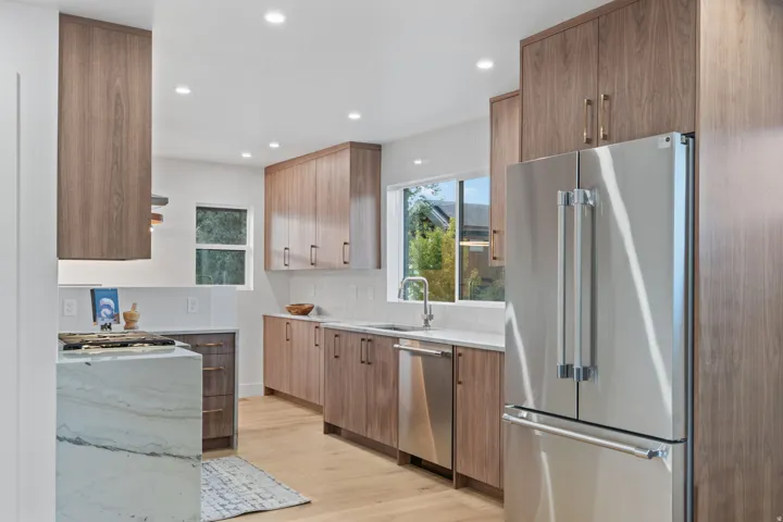Kitchen featuring wood-finish cabinetry, stainless steel appliances, white subway tile backsplash, and recessed lighting
