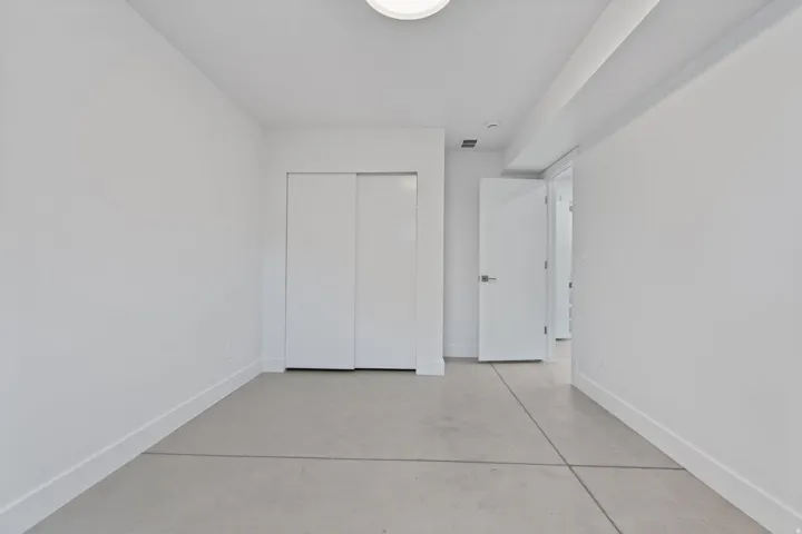 Concrete flooring, white walls, white sliding closet doors, white door, and recessed lighting
