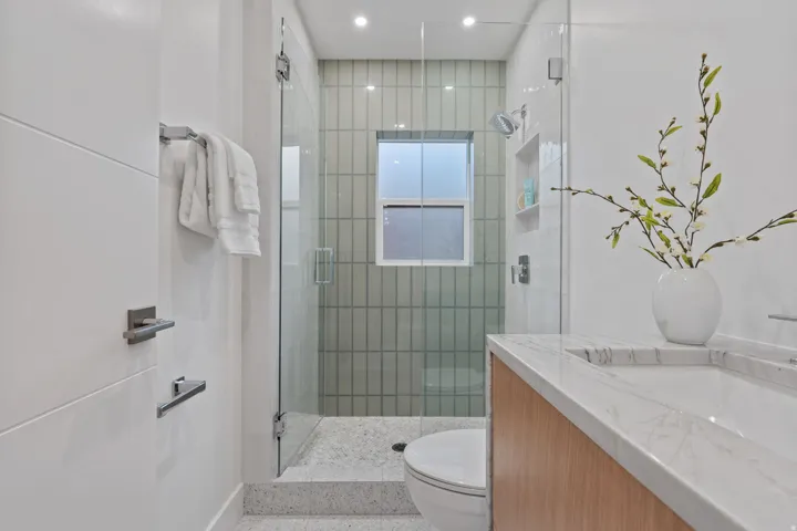 Glass-enclosed shower with vertical tile surround and built-in niche