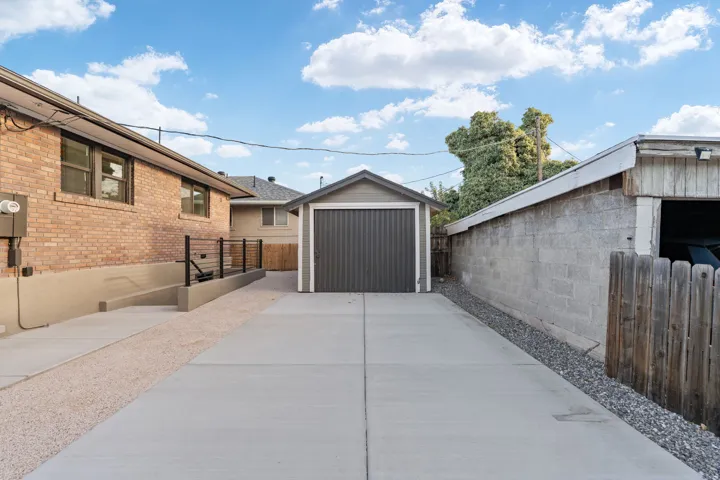 Detached garage structure with a roll-up door, concrete driveway, and gravel accents