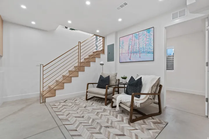 Open-tread staircase with metal rod railing, light wood-finish flooring, recessed ceiling lighting, and light-toned walls
