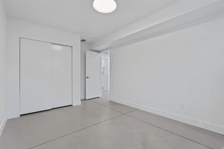 Smooth concrete flooring, white walls, and a flush-mount ceiling light