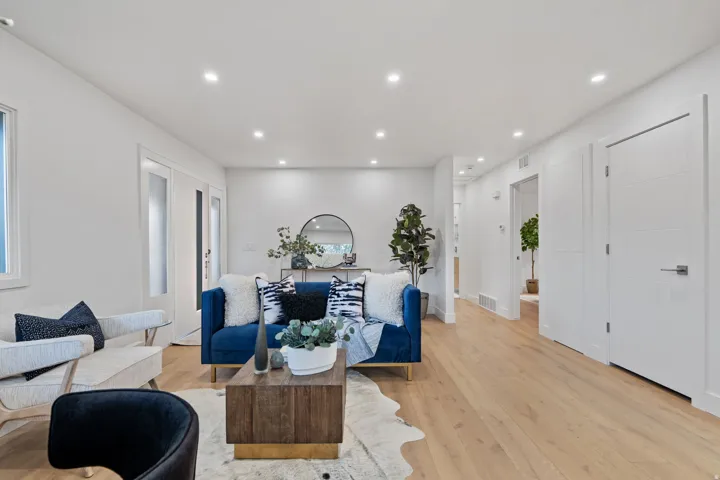 Recessed lighting, wood-finish flooring, white walls, white trim, and a white interior door