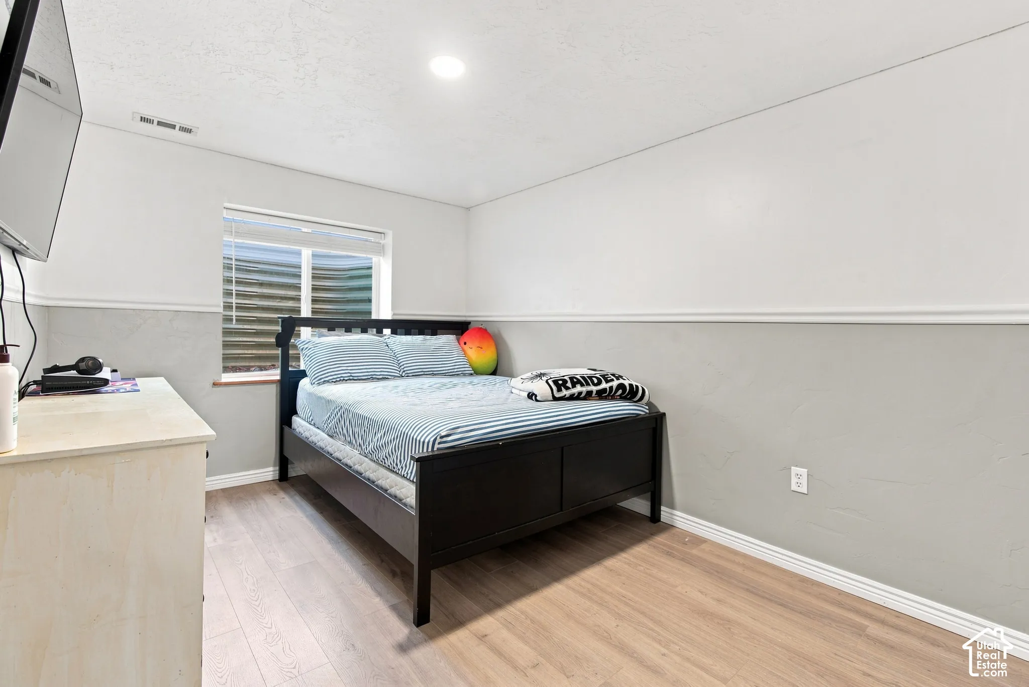 Light-toned wood-finish flooring, two-tone wall treatment, and an egress window