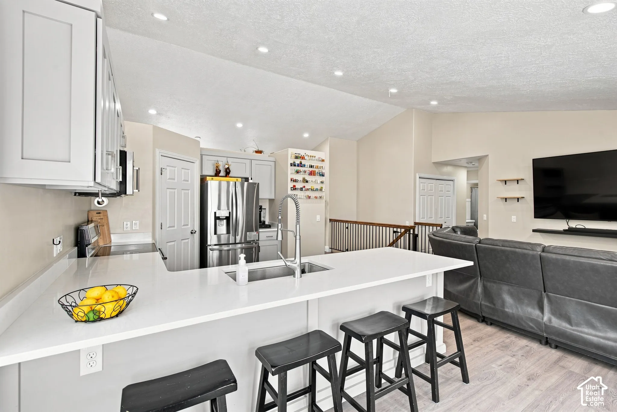 Kitchen featuring white shaker cabinetry, stainless steel appliances, and a central island with a sink