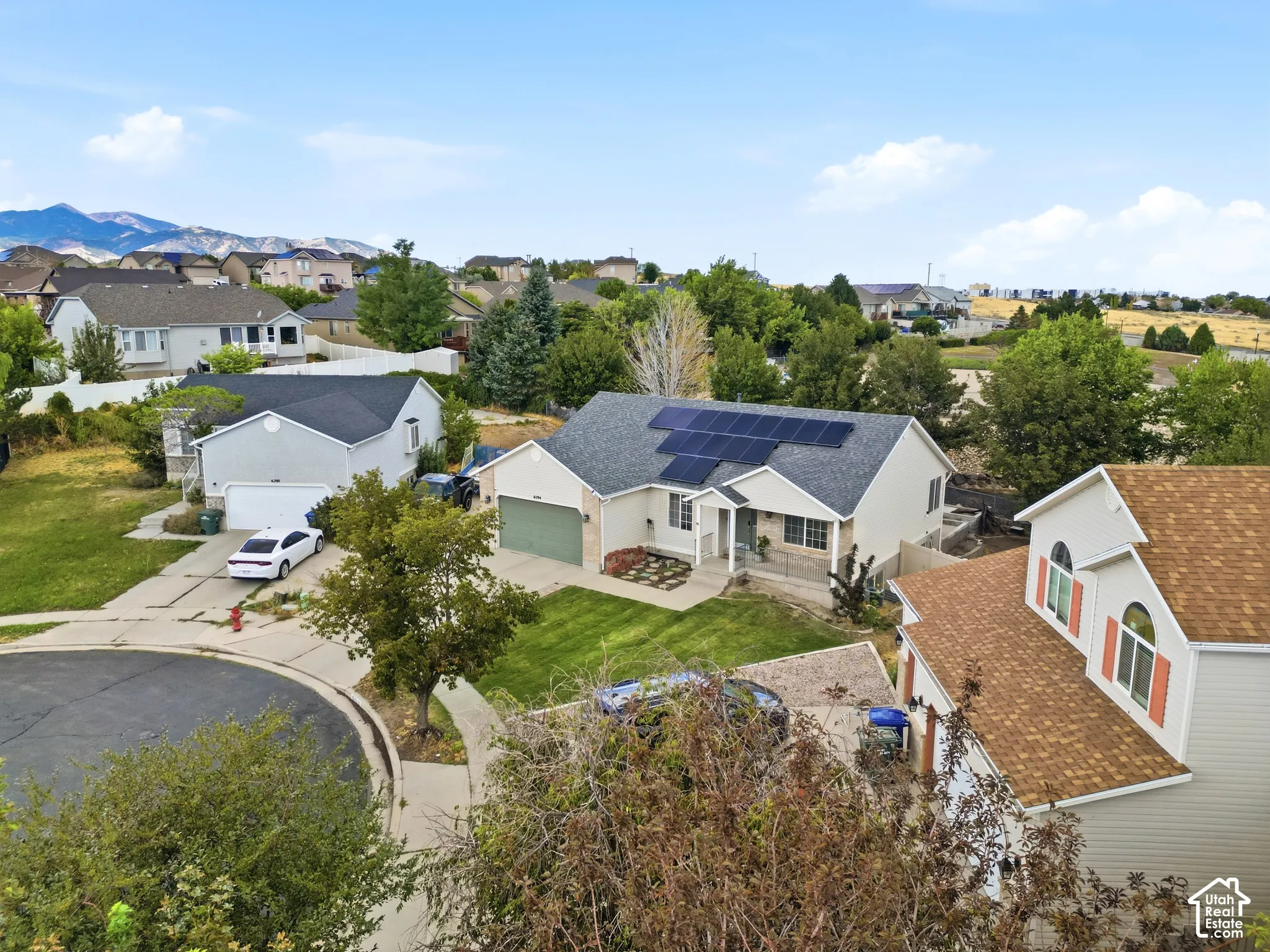 Single-story residence featuring a gray roof, solar panels, and a landscaped front yard with a paved driveway