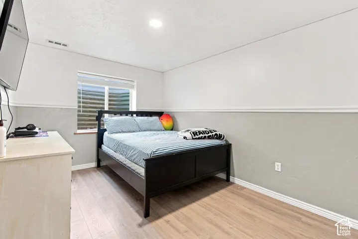 Light-toned wood-finish flooring, two-tone wall treatment, and an egress window