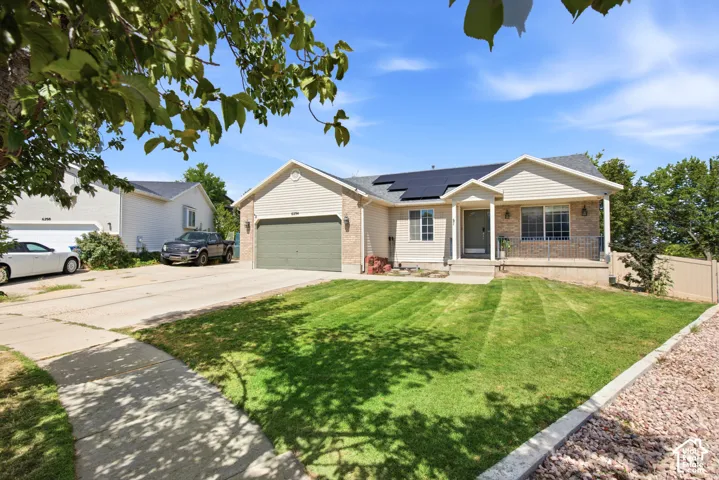 Siding exterior with stone accents, covered front porch with railing, attached two-car garage, concrete driveway, and front lawn