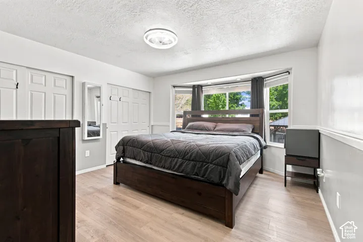Recessed bay window with dark window treatments, light wood-finish flooring, and white bifold closet doors