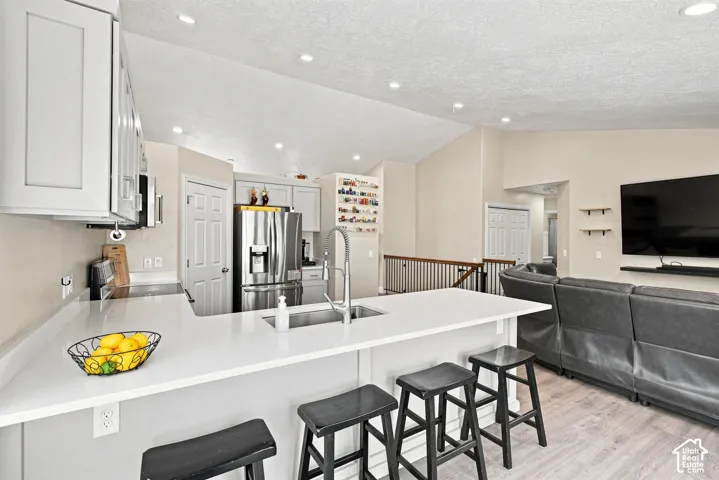 Kitchen featuring white shaker cabinetry, stainless steel appliances, and a central island with a sink