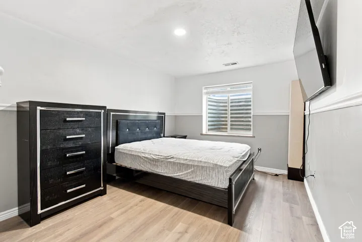 Wood-finish flooring with a window, recessed lighting, and crown molding