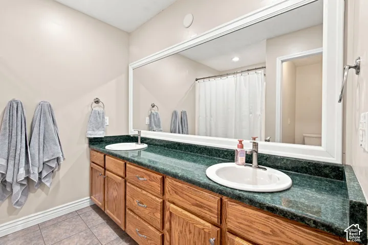 Double vanity with wood-finish cabinetry, dual undermount sinks, and a dark green countertop