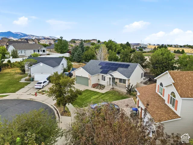 Single-story residence featuring a gray roof, solar panels, and a landscaped front yard with a paved driveway
