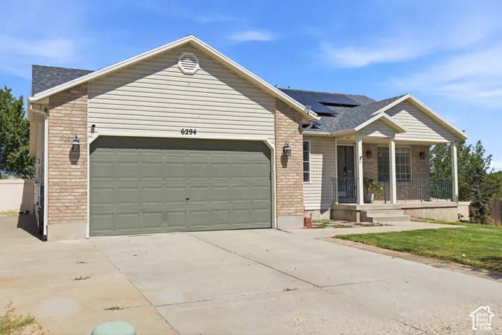 Two-car garage, brick and siding exterior, covered front entry, concrete driveway, and solar panels