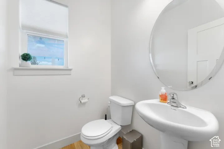 White pedestal sink with chrome faucet and circular wall mirror