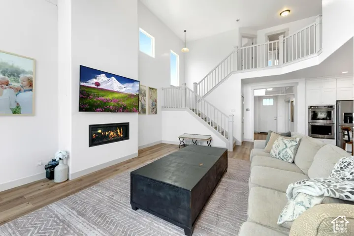 Two-story living area with wood-finish flooring, a contemporary fireplace, and a second-story landing with railing