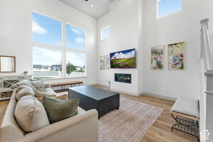 Two-story living area featuring tall windows, wood-finish flooring, a contemporary fireplace, built-in media wall, and a staircase with painted balusters