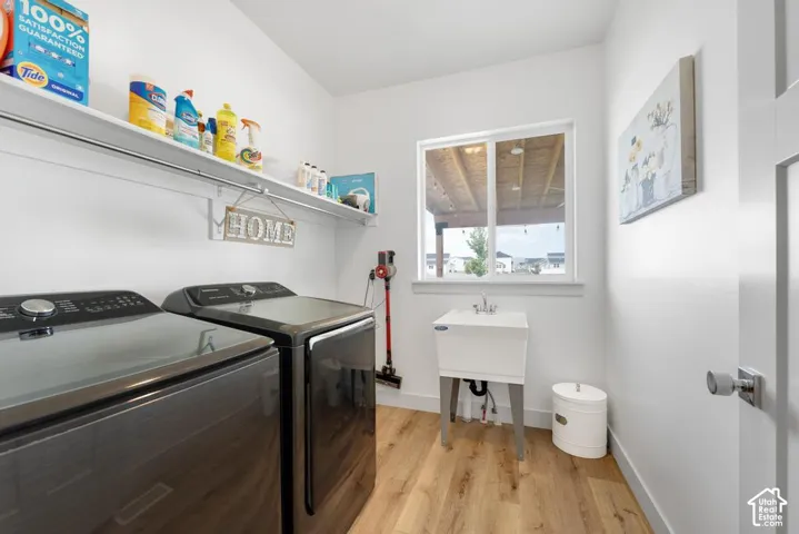 Laundry area featuring wood-finish flooring, a utility sink, and built-in shelving with a hanging rod