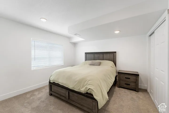 Plush carpeting, recessed lighting, window with blinds, and white bi-fold closet doors
