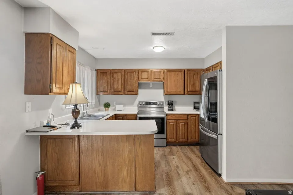 Kitchen featuring wood-finish cabinetry, stainless steel appliances, white countertops, and wood-finish flooring