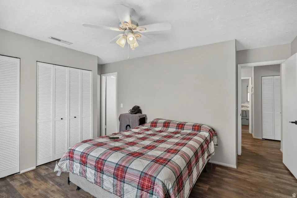 Wood-finish flooring, white louvered closet doors, and an overhead ceiling fan with integrated lighting