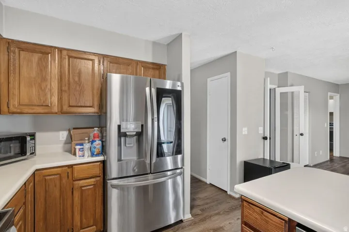 Kitchen featuring wood cabinetry, light countertops, and wood-finish flooring