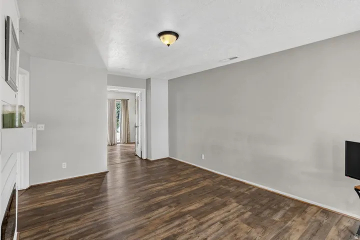 Wood-finish flooring throughout, light gray wall finishes, recessed lighting, and a white mantel
