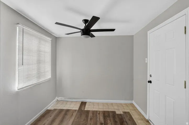 Room featuring a window with blinds, ceiling fan, and paneled door