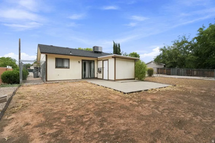 Rear exterior featuring a sliding glass door, a detached shed, and a concrete patio