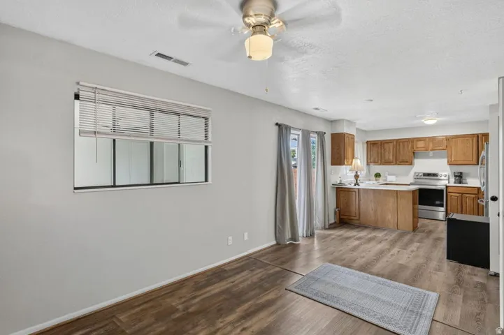 Wood-finish flooring throughout, light gray wall finishes, kitchen with wood cabinetry, stainless steel appliances, and a central island