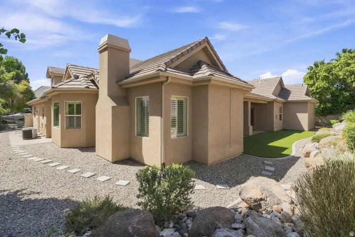 Stucco exterior with a tile roof, an outdoor chimney, and multiple windows with shutters