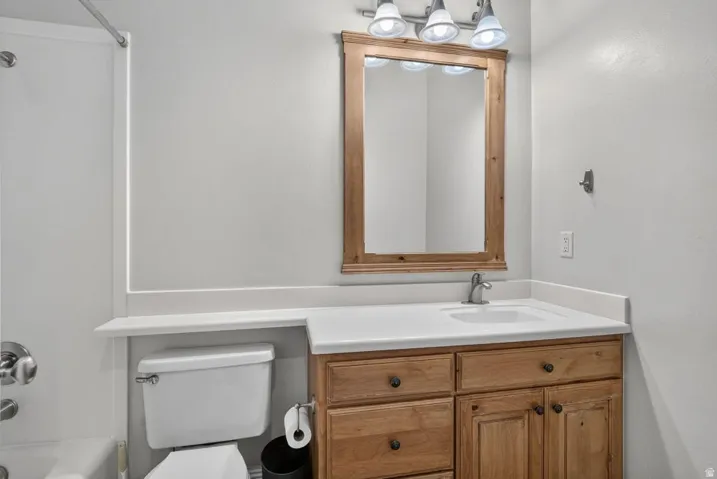 Bathroom featuring a single vanity with wood-finish cabinetry, a white countertop, and a rectangular undermount sink