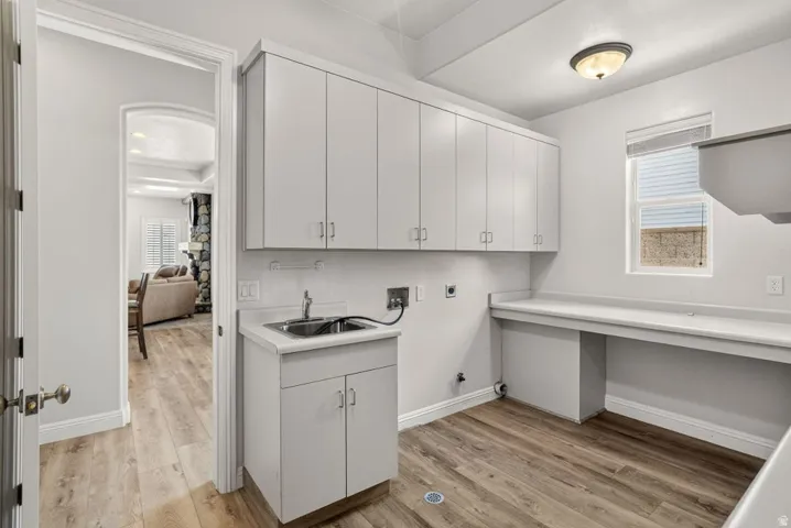 Wood-finish flooring, white cabinetry, integrated sink, built-in countertop, and an arched doorway