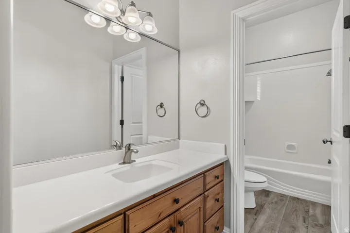 Single vanity with a white countertop and integrated sink, brushed nickel faucet, large wall mirror, and a five-light vanity fixture