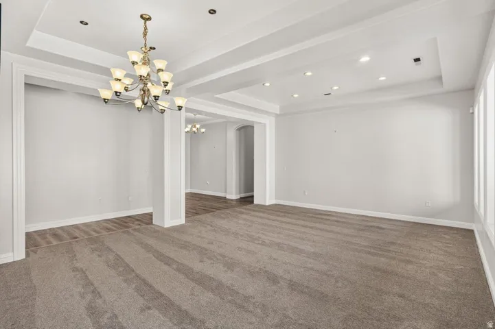 Recessed lighting, crown molding, a decorative chandelier, and a coffered ceiling