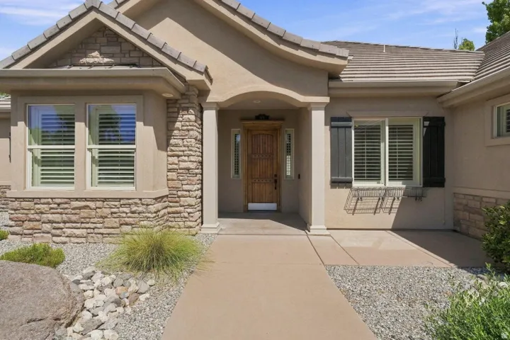 Stucco exterior with stone accents, wood plank shutters, and a tile roof