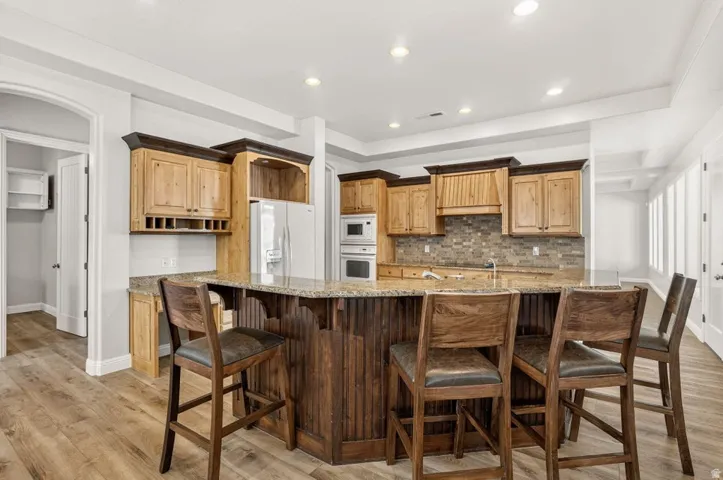 Wood-finish flooring throughout, recessed lighting, and a kitchen island with seating