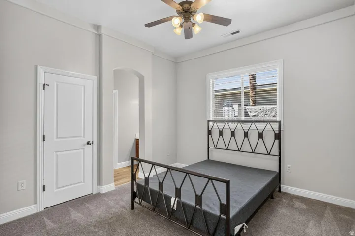 Recessed window with blinds, ceiling fan with integrated lighting, arched doorway, and neutral tone walls