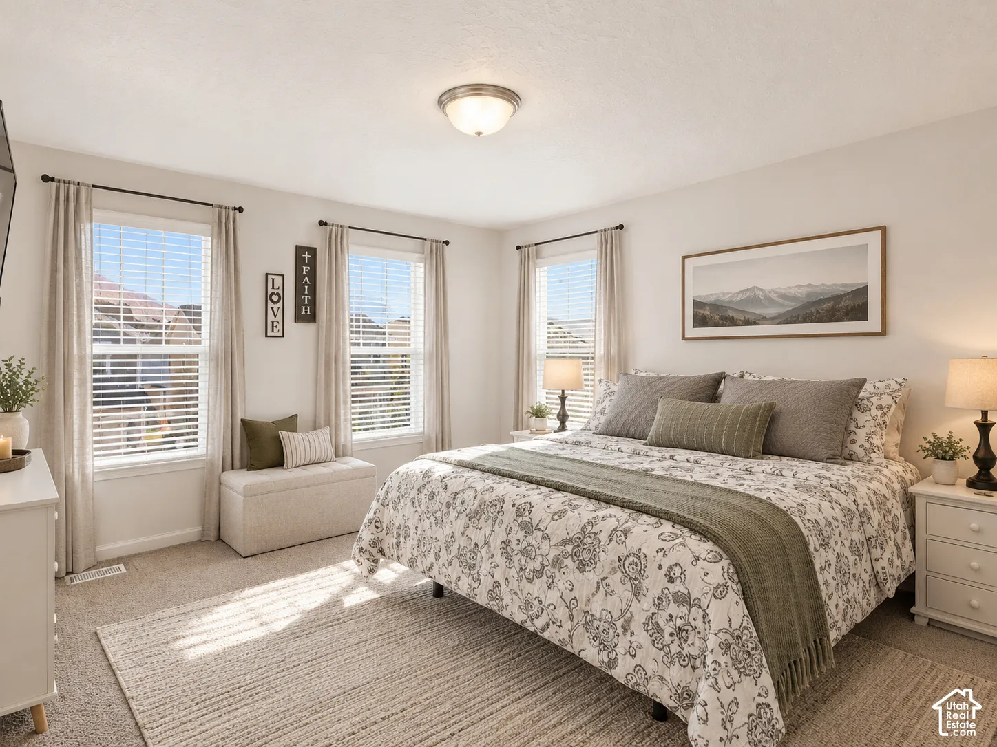 Neutral-toned bedroom featuring wall-to-wall carpeting, three windows with natural light, and a flush-mount ceiling light fixture