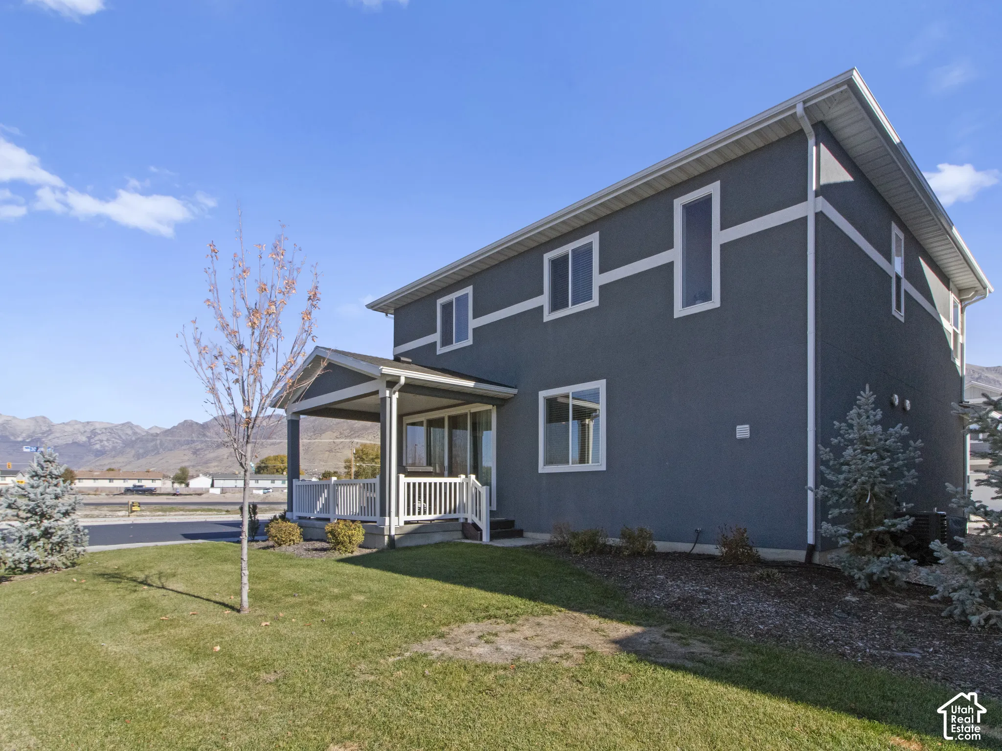 Two-story exterior with stucco siding, covered porch, multiple windows, and a landscaped yard
