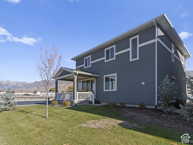Two-story exterior with stucco siding, covered porch, multiple windows, and a landscaped yard