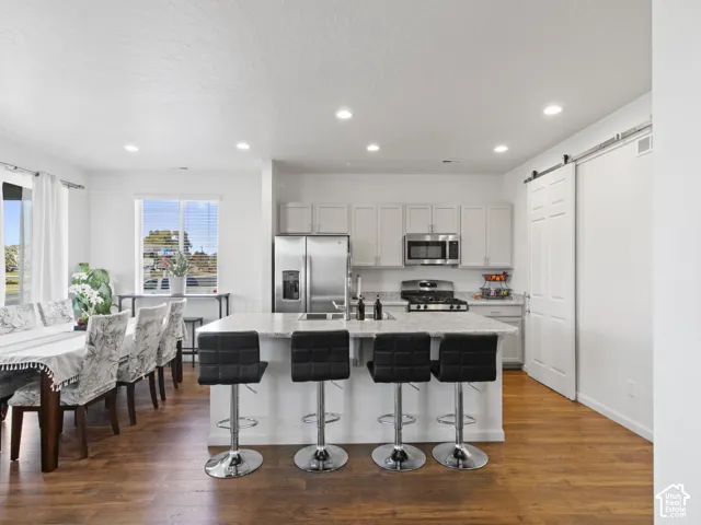 Open-concept kitchen and dining area featuring wood-finish flooring, recessed lighting, and a kitchen island with seating