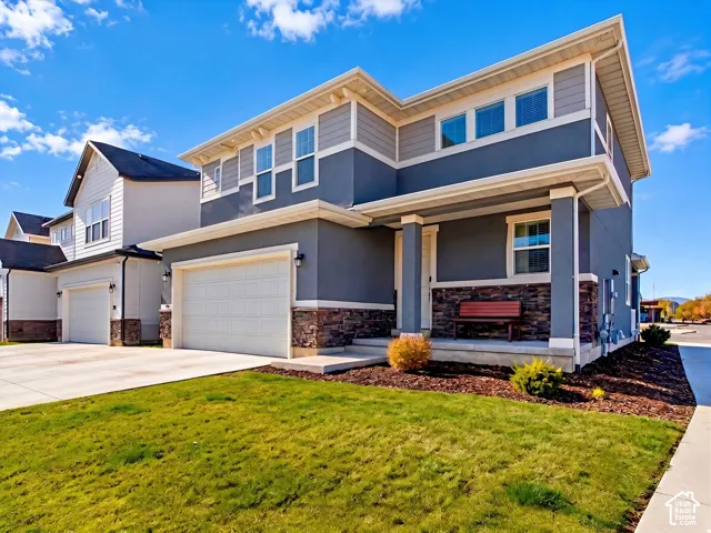 Two-story exterior featuring a mix of horizontal lap siding and stucco finishes, stone veneer accents, an attached two-car garage, and a covered front porch