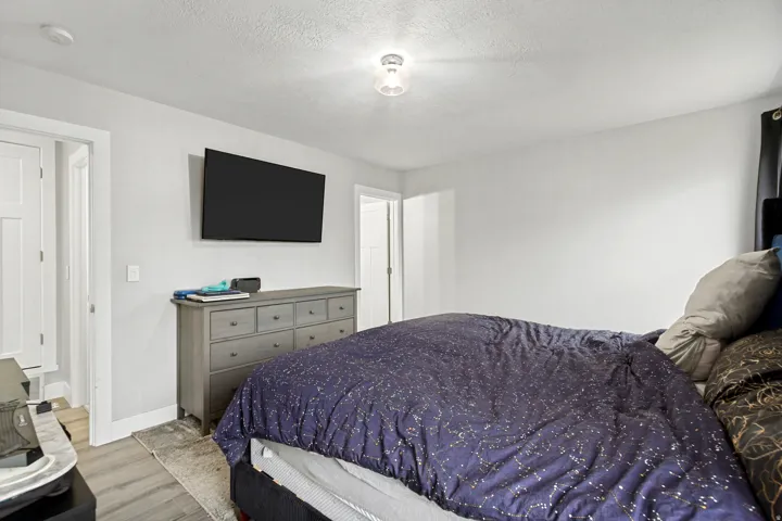 White walls with wood-finish flooring, featuring a recessed white paneled door