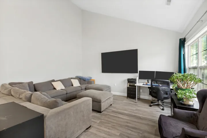 Vaulted ceiling, wood-finish flooring, large windows, and a dedicated workspace