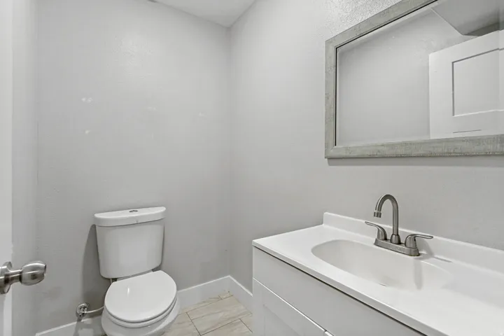 White vanity with an integrated sink, brushed nickel faucet, and a framed mirror