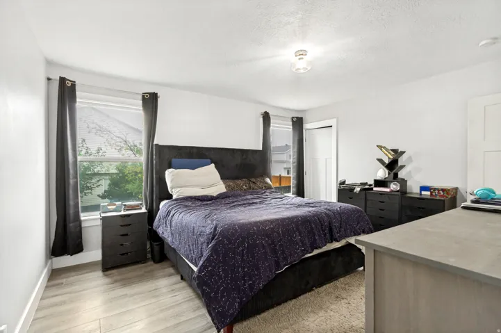 Recessed window with natural light, wood-finish flooring, white walls, and a ceiling-mounted light fixture