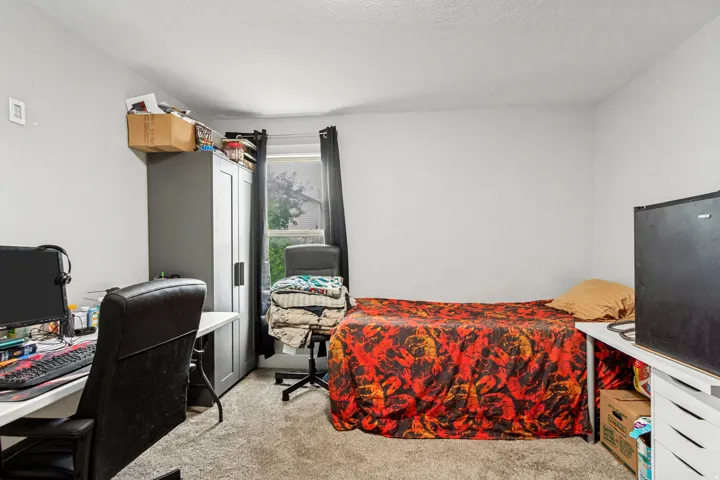 Neutral wall color, carpet flooring, window with dark drapes, and overhead lighting