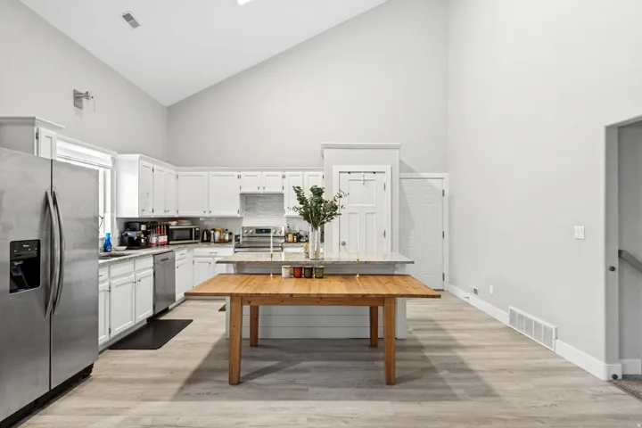Spacious kitchen featuring white cabinetry, stainless steel appliances, wood countertops, and abundant natural light from recessed ceiling fixtures