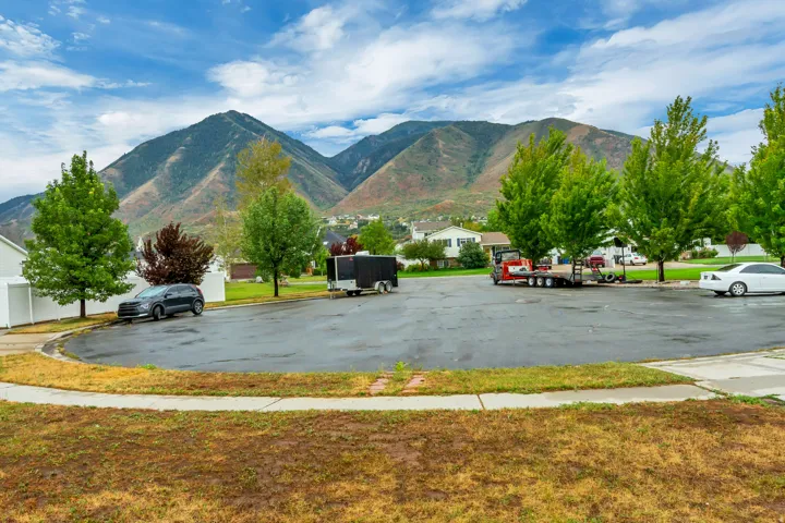 Paved cul-de-sac with mature trees, surrounded by residential properties, and a mountain backdrop